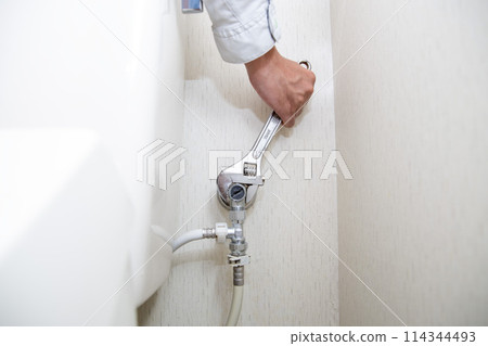 A man repairing a toilet A man repairing a toilet 114344493