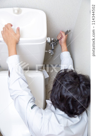 A man repairing a toilet A man repairing a toilet 114344502