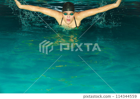 Woman athlete swimming butterfly stroke in pool. 114344559