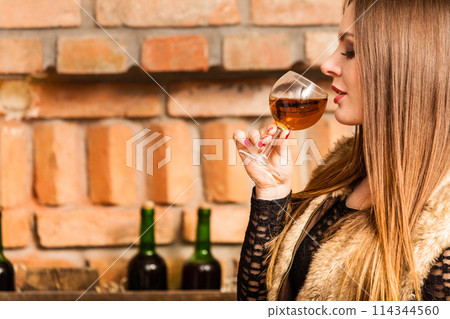 Woman tasting wine in rural cottage interior 114344560