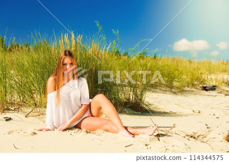 Young woman posing in grassy dune 114344575