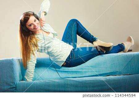 Woman with tablet headphones laying on couch 114344594