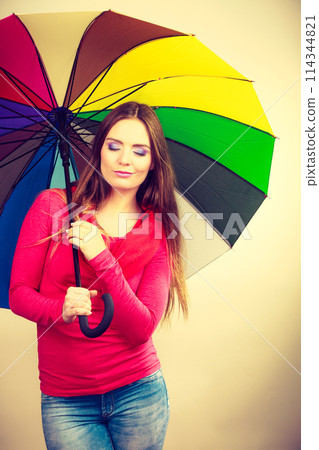 Woman standing under multicolored umbrella 114344821
