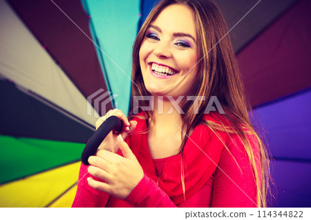 Woman standing under multicolored umbrella 114344822