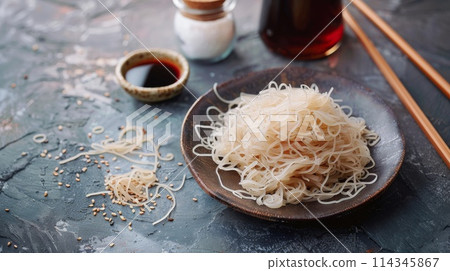 Japanese shirataki noodles with soy sauce and chopsticks on dark background 114345867