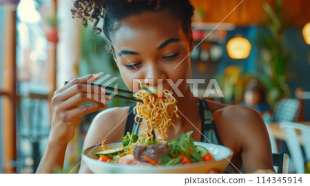 Young african american woman eating soy noodles in restaurant. Traditional food concept 114345914