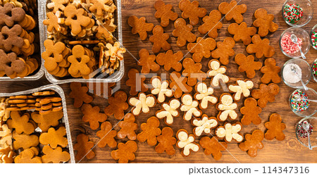 Crafting gingerbread cookie sandwiches with eggnog buttercream, presented on a rustic wooden table for Christmas gifting. Crafting gingerbread cookie sandwiches with eggnog buttercream, presented on a rustic wooden table for Christmas gifting. 114347316