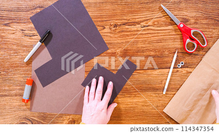 Step by step. Flat lay. Teacher guides online class through making a paper puppet from a brown bag, creatively using a wooden surface as a workspace. Step by step. Flat lay. Teacher guides online class through making a paper puppet from a brown bag, creatively using a wooden surface as a workspace. 114347354
