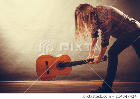 Rock musician destroys his guitar. 114347424