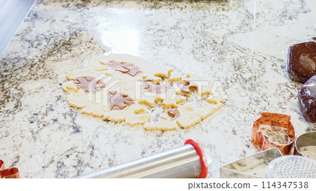 Using various festive cookie cutters, we're cutting out charming gingerbread cookies from the rolled dough on the sleek marble counter, bringing holiday cheer to the modern kitchen. 114347538