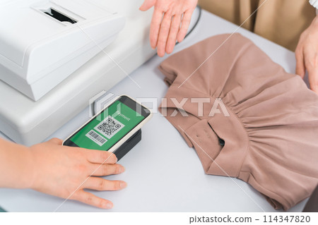 在服裝店/服裝店使用智能手機進行二維碼支付的女士 114347820