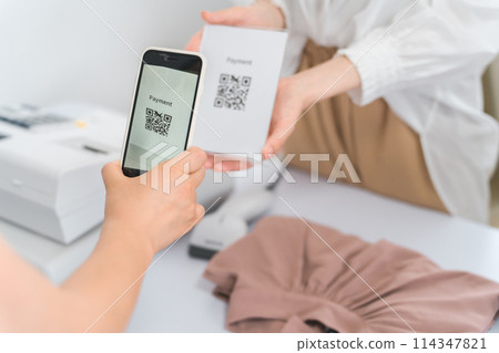在服裝店/服裝店使用智能手機進行二維碼支付的女士 114347821