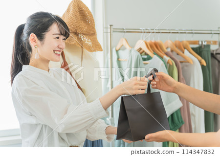 精選商店/服裝店微笑的女店員將紙袋遞給顧客 114347832