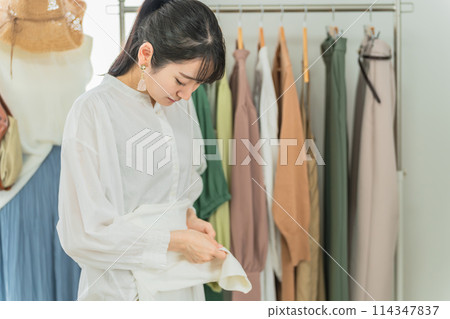 A shop that folds clothes, a salesperson working in a clothing store, an employee, an Asian woman in a shop clerk A shop that folds clothes, a salesperson working in a clothing store, an employee, an Asian woman in a shop clerk 114347837