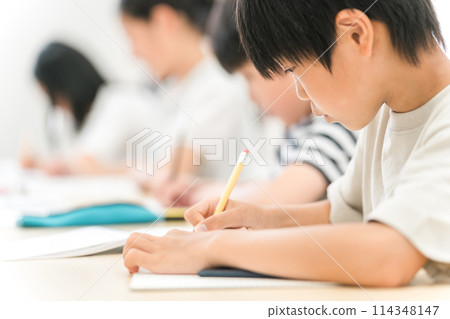 Boys and elementary school students writing in notebooks during cram school and school classes 114348147