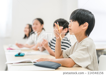 Elementary school boys and girls with serious expressions taking classes at cram school or school Elementary school boys and girls with serious expressions taking classes at cram school or school 114348156