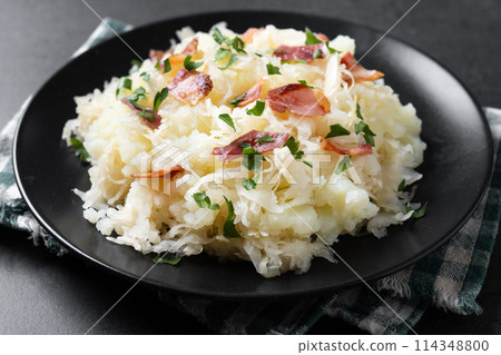 Slovak potato dumplings halusky with steamed sauerkraut and bacon on black background Slovak potato dumplings halusky with steamed sauerkraut and bacon on black background 114348800