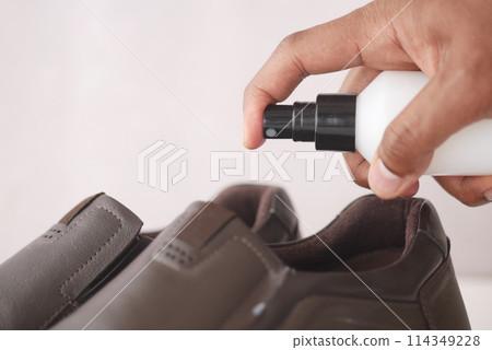 spraying deodorant on sweaty shoes. 114349228
