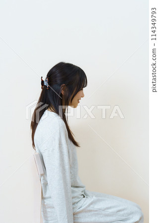 Young woman sitting on a chair and exercising 114349793