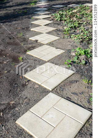Paving concrete tile garden path in bright sunshine. Paving concrete tile garden path in bright sunshine. 114352899