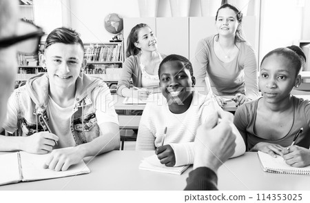 Teacher calls student at far desk to answer. Focus on girl on right above 114353025