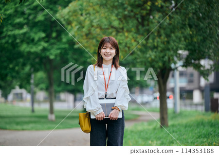 A young woman carrying a laptop and a notebook A young woman carrying a laptop and a notebook 114353188