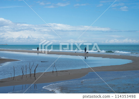 Gruissan - France - 27 April 2024 - silhouettes of people standing on the beach on beautiful cloudy sky background Gruissan - France - 27 April 2024 - silhouettes of people standing on the beach on beautiful cloudy sky background 114353498