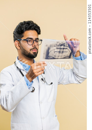 Indian young doctor orthodontist man examines a panoramic x-ray picture of the jaw teeth stomatology Indian young doctor orthodontist man examines a panoramic x-ray picture of the jaw teeth stomatology 114353501