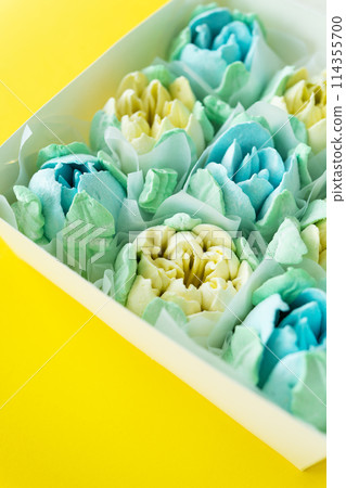 Box of colorful desserts in the shape of flowers on a two-color background. Marshmallow in the form of a rose. Box of colorful desserts in the shape of flowers on a two-color background. Marshmallow in the form of a rose. 114355700
