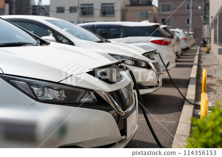 Electric EV car parked in the parking lot while plugged in for charging 114356153
