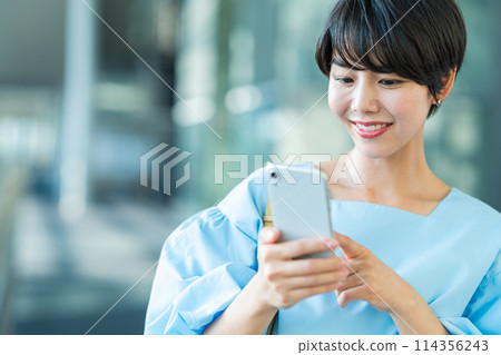 一名年輕女子正在操作智慧型手機。 114356243