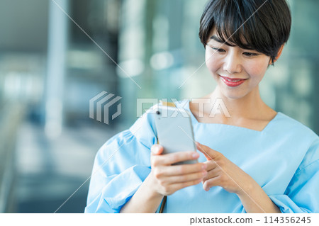 A young woman operating a smartphone. 114356245