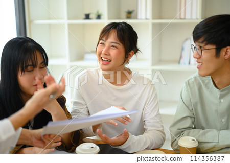 Cheerful Asian college students working on group assignment in library Cheerful Asian college students working on group assignment in library 114356387