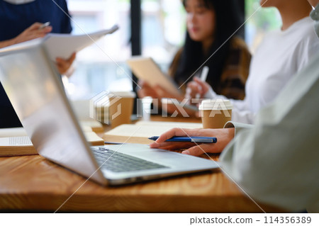 University students using laptop while working together on their assignment at library University students using laptop while working together on their assignment at library 114356389