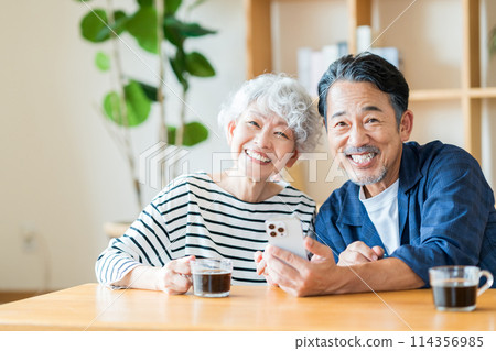 A senior couple looking at their smartphones together. A senior couple looking at their smartphones together. 114356985