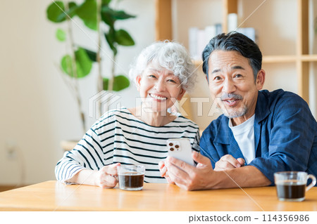 A senior couple looking at their smartphones together. 114356986