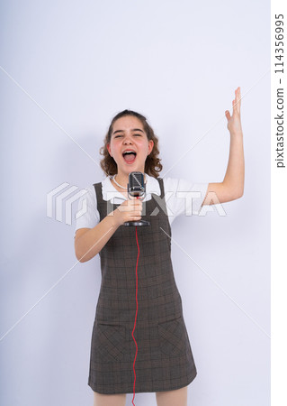 With microphone in hand positive teenage girl singer, young karaoke singer hold microphone. With microphone in hand positive teenage girl singer, young karaoke singer hold microphone. 114356995