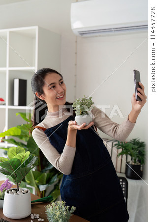 Hobby, asian young woman using mobile phone taking photo of pot, houseplant with dirt soil on table at home 114357728