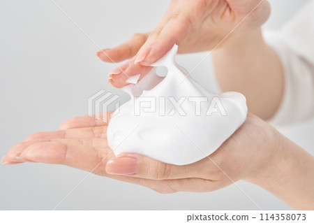 一個女人的手將一團細泡沫放在她的手掌上 114358073