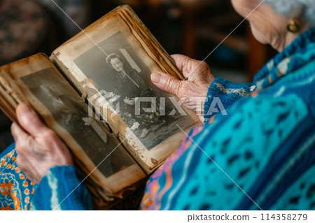 Senior Woman Reliving Memories by Browsing Through an Old Family Album 114358279