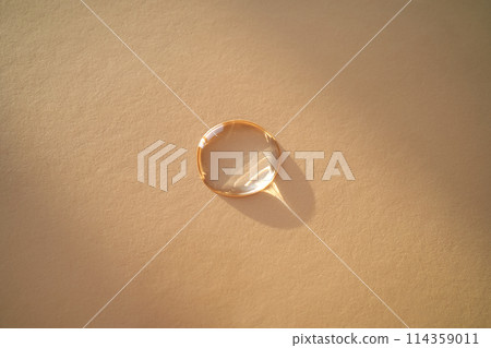 Beautiful volumetric drop of cosmetic product on a beige background. Beautiful volumetric drop of cosmetic product on a beige background. 114359011