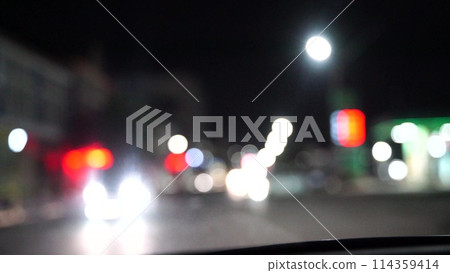 Blurred car lights bokeh in the evening city. Defocused headlights and street lighting at night. Moving bokeh circles of cars at night. Blurred city traffic background Blurred car lights bokeh in the evening city. Defocused headlights and street lighting at night. Moving bokeh circles of cars at night. Blurred city traffic background 114359414