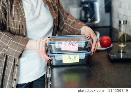 Healthy diet plan for weight loss, daily ready meal menu. Plus size young Woman holding lunch boxes just cooked in advance, ready to be served. Containers with eco healthy food. Pre-cooking concept. Healthy diet plan for weight loss, daily ready meal menu. Plus size young Woman holding lunch boxes just cooked in advance, ready to be served. Containers with eco healthy food. Pre-cooking concept. 114359849