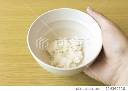 A man's hand holding a bowl of rice. An image of poverty A man's hand holding a bowl of rice. An image of poverty 114360318