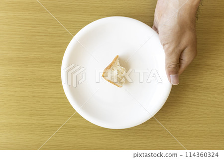 A man's hand holding a piece of bread on a plate. An image of poverty A man's hand holding a piece of bread on a plate. An image of poverty 114360324