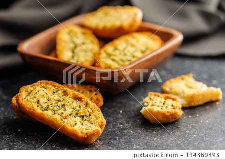 Garlic crisp bread Slices Topped With Herbs on black table. 114360393