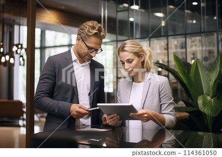 businessman and businesswoman discussing a project on a tablet in the office businessman and businesswoman discussing a project on a tablet in the office 114361050