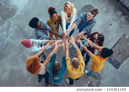 group of people standing in a circle raises their hands up 114361108