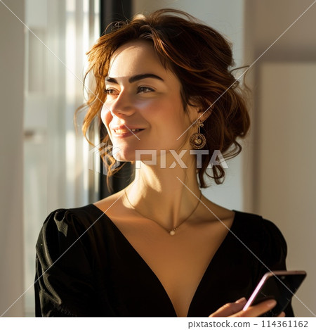 attractive smiling woman in dress in office with smartphone in hand 114361162