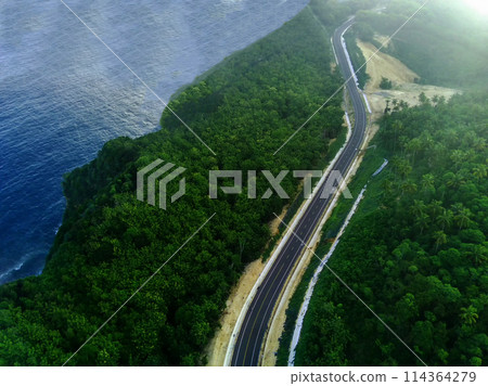 a curvy coastal road snaking along a bright blue ocean. 114364279